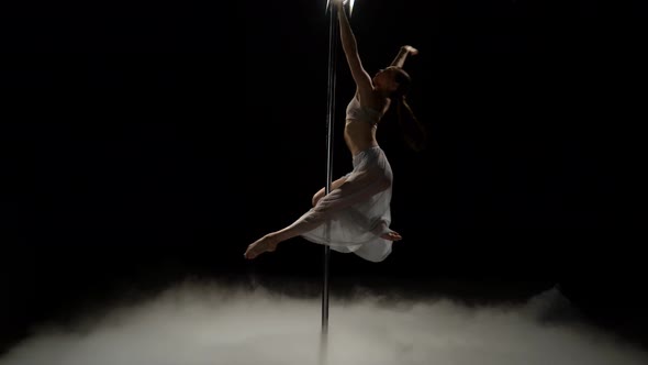 Girl Dancing on a Pole in the Dark Smoke Studio. Black Smoke Background