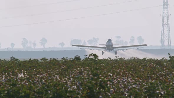 Crop duster spraying chemicals over a cotton field - slow motion