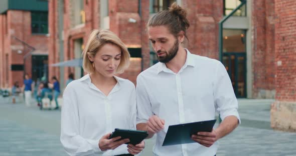 Bearded Businessman and Blonde Woman in White Shirts Meeting and Talking outdoors.