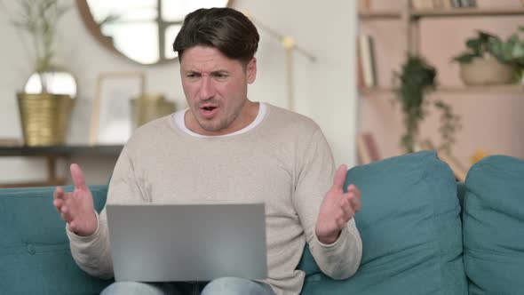 Middle Aged Man Reacting to Loss on Laptop  at Home