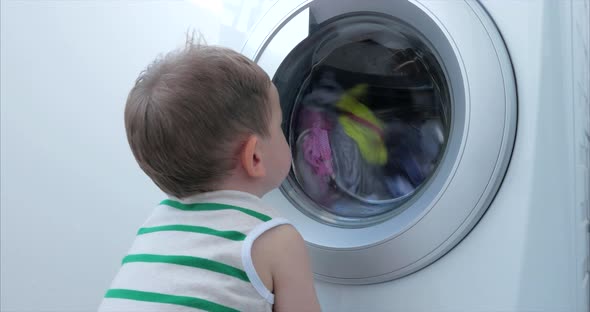 Cute Little Boy Looks Inside the Washing Machine. Cylinder Spinning Machine. Concept Laundry Washing