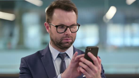 Middle Aged Businessman Scrolling on Smartphone