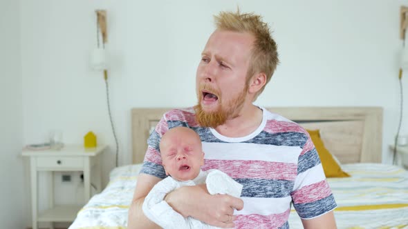 father cries with a sleeping baby in his arms