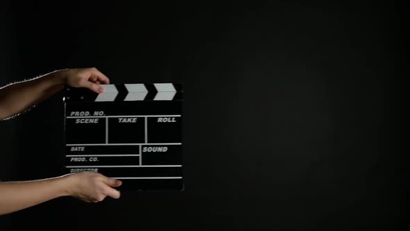 Hands with Movie Clapper Board, on Black, Slow Motion