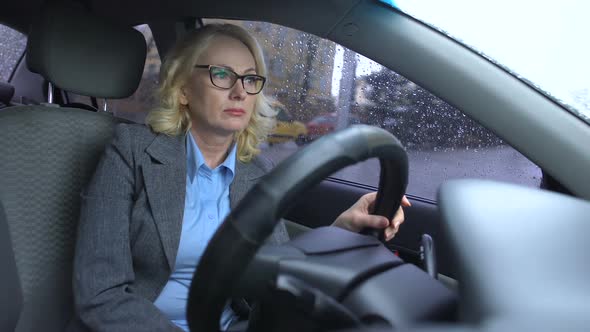Exhausted Elderly Woman in Suit Sitting in Car, Rain Drops on Window, Depression