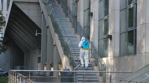 A Professional Cleaner in a Protective Suit and a Respirator Disinfects Outdoor Covid-19. Corona