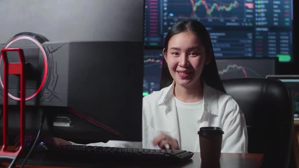 Asian Female Stock Market Broker Working On Computer And Smiling To Camera