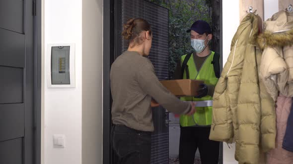 A courier in a medical mask delivered a package of food to the customer's home before the door