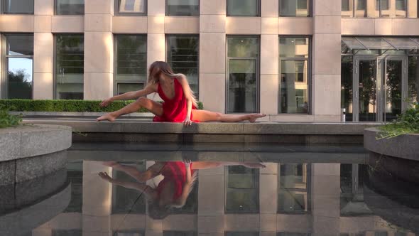 Beautiful Young Girl Dancing on the Street of a Modern City and Is Reflected in the Water. She Is