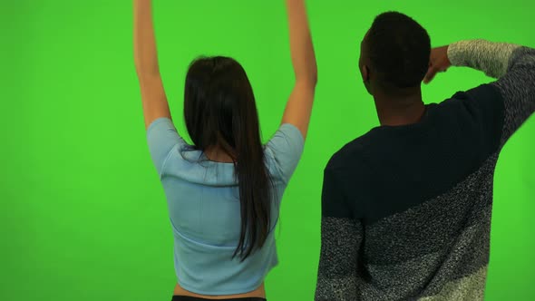 An Asian Woman and a Black Woman Cheer with Their Backs To the Camera - Green Screen Studio
