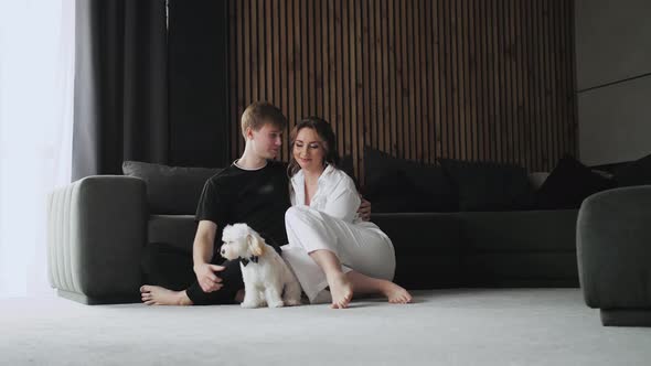 A Lovely Couple with Dog Sitting on the Floor Spouses Kissing and Enjoying of Each Other