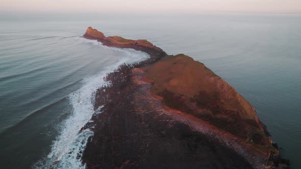 AERIAL: Close circle of Worm's Head during ornage sunrise, Rhossili Gower, 4k Drone