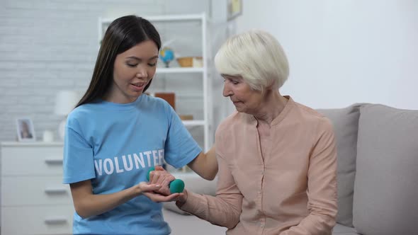 Social Worker Assisting Old Woman Making Exercise With Dumbbell, Rehabilitation