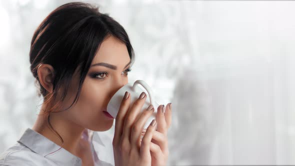 Medium Closeup Happy Pleasant Young Woman Drinking Coffee or Tea Holding White Mug