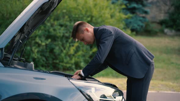 Young Businessman Repairing Broken Car in Outdoor