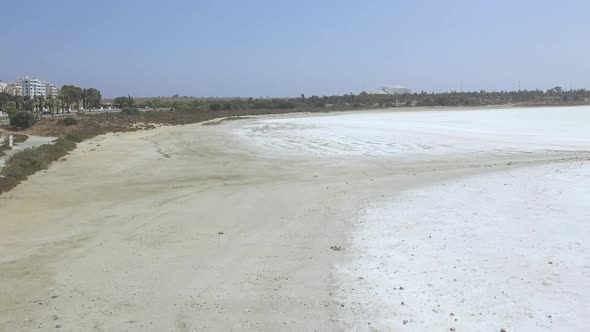 Aerial drone shot flying over the beach coast of the salt lakes in Cyprus with buildings and roads n