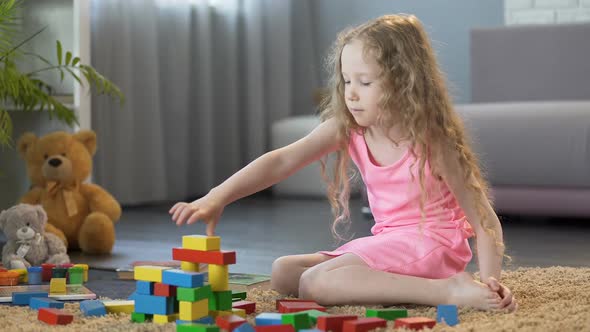 Young Girl Constructing Toy Tower, Playing Organic Wooden Blocks at Home