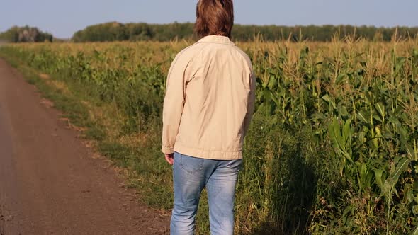 Farmer Man Walks Along a Dirt Road Between Agricultural Fields at Sunset Slow Motion