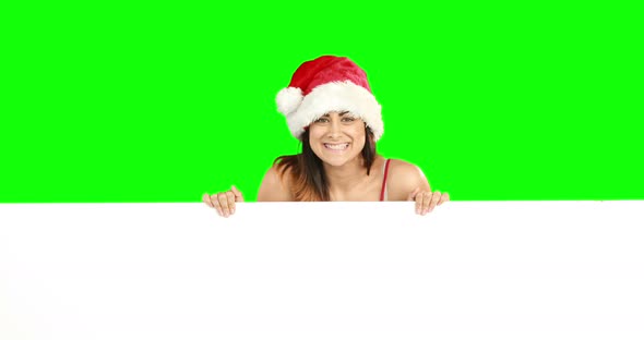 Beauty brunette in santa hat showing white poster 4k