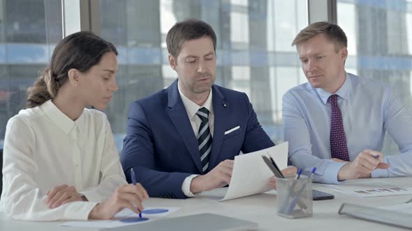 Middle Aged Businessman Sharing Plan on Documents with His Assistants on Office Table