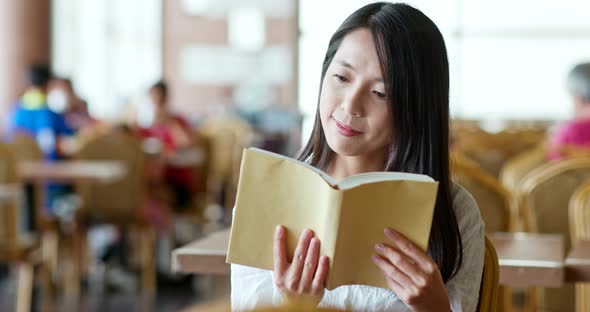 Woman reading book inside coffee shop