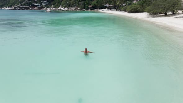 A Panning Shot of a Beautiful Girl Making Splash in the Sea and Laughing