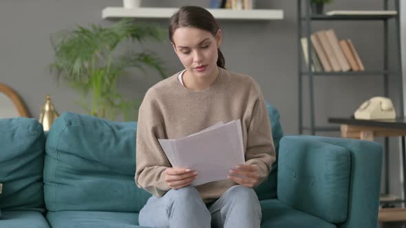 Woman Reading Documents on Sofa