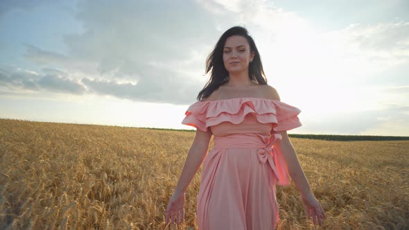 A Beautiful Girl in a Dress Walks Through a Wheat Field