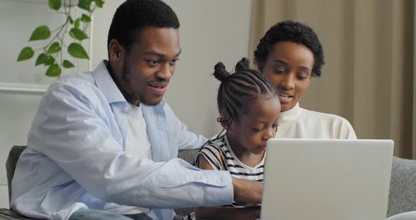 Young Afro American Parents Mom and Dad Family Teach Little Cute Daughter Girl To Use Laptop