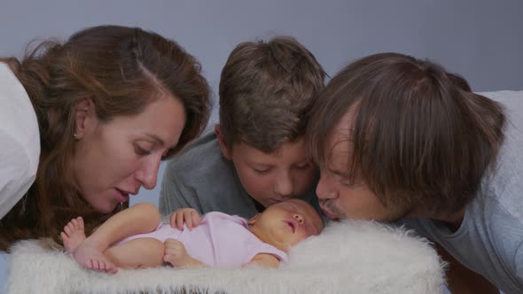 Mother Father and Son Kiss a Newborn Girl. Replenishment in the Family. Family Concept.