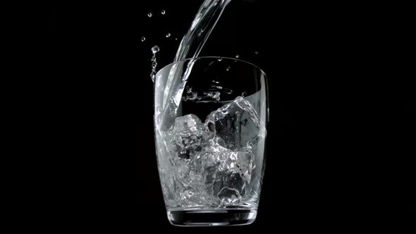 Pouring water into glass with ice cubes, Slow Motion alt