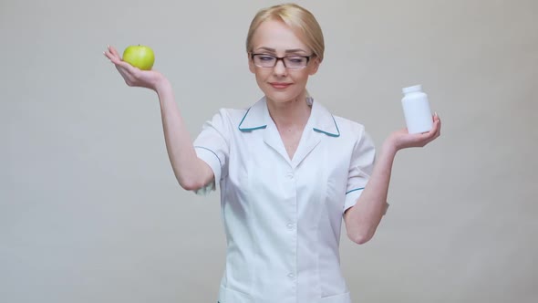 Nutritionist Doctor Healthy Lifestyle Concept - Holding Organic Green Apple and Jar of Vitamin Pills