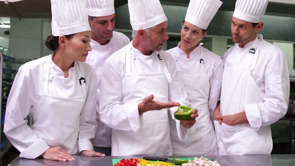 Team of Chefs Watching Head Chef Slicing Vegetables