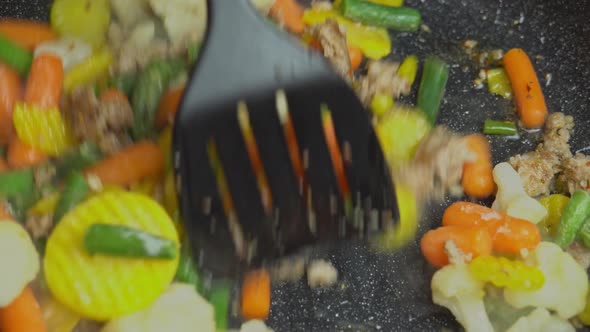 Close up view of steaming frying pan and mixed vegetables with frying minced.