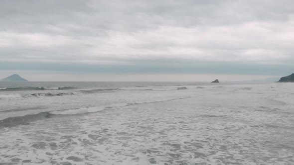 Lateral drone footage of the beach, cloudy day, waves, agitaded sea, landscape of Juquehy, Ubatuba,