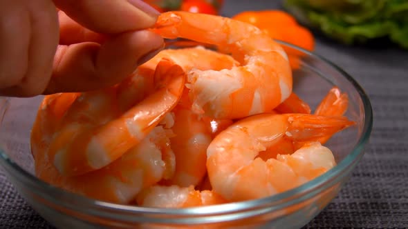 Hand Puts One Peeled Shrimp in a Glass Bowl