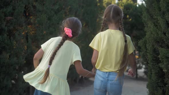 Little Girls Running in a Hedge Maze Two Sisters Kids Hold Hands and Run in Big Green Labyrinth in