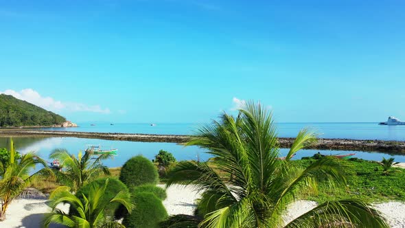 Beautiful tropical plants and palms on garden of holiday resort with white sandy beach washed by cal