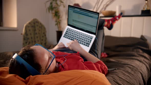 Young Man Lying on the Bed and Searching the Internet