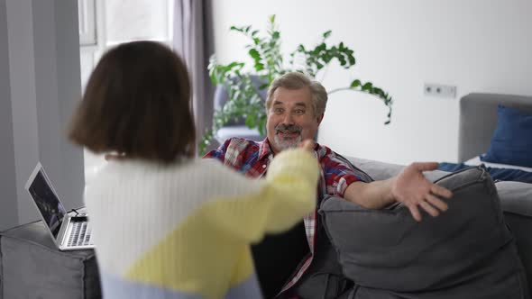 Elderly Man Sitting on Couch When His Granddaughter Running Up and Hugging Him