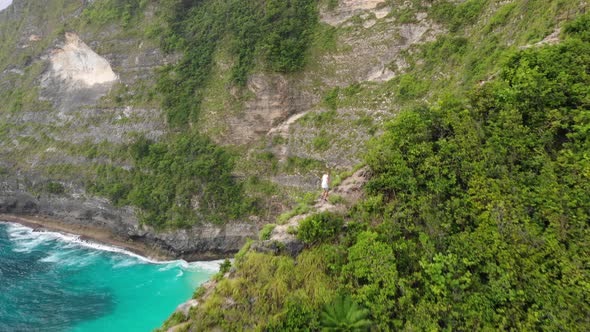 Young Man Hiking On Edge Of the tropical Mountain Cliff Extreme Sport concept. Aerial drone high ang