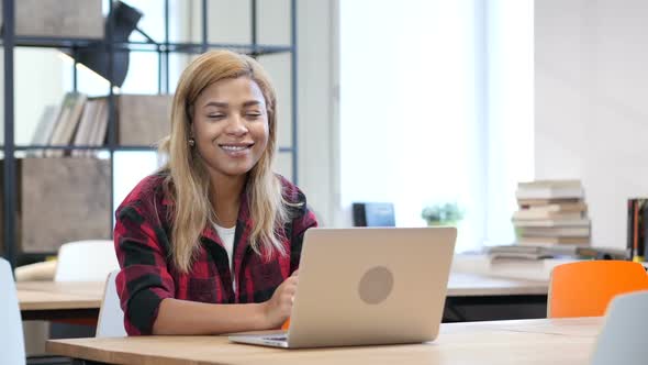 Black Woman Working on Laptop, Smiling toward Camera