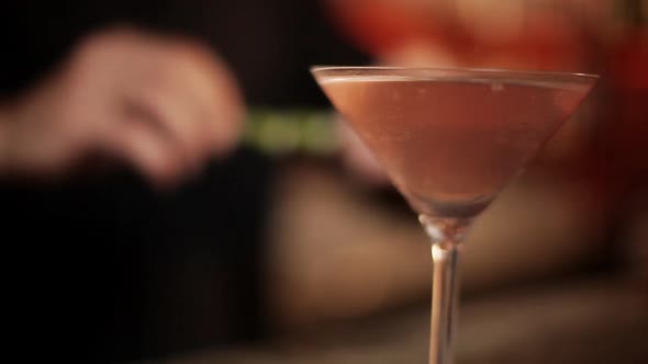 Bartender adding lime rind garnish to cosmopolitan