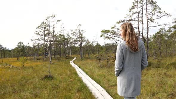 Young Woman Walking on Wooden Boardwalk Through Bog Swamp Land