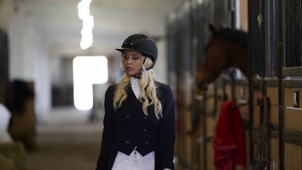 Female Horse Rider is Walking in Stable and Resting Before Championship Beautiful Blonde Woman