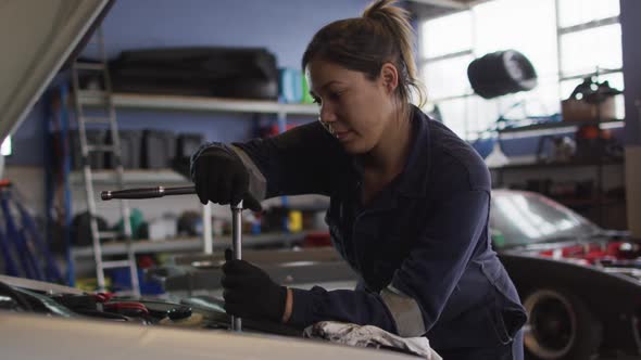 Female mechanic using a wrench to repair a car at a car service station