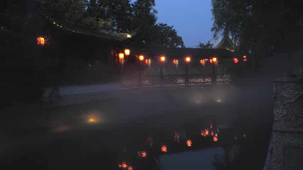 Night View of a Pagoda and the Pond with Dense Fog Smoke on the Surface in the Ancient Town of Mudu
