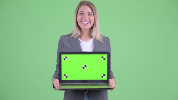 Happy Young Blonde Businesswoman Showing Laptop and Looking Surprised