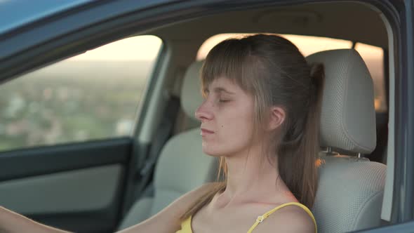 Young woman driver relaxing behind the wheel of her car.