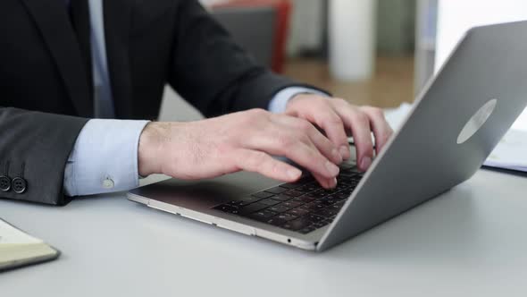 Closeup View of Male Hands Typing on Laptop Keyboard